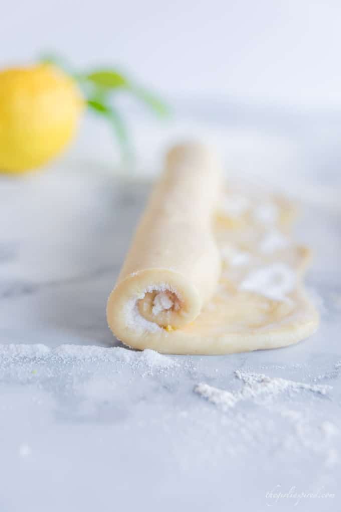 sweet dough with sugar and lemon zest in partially rolled length of dough with lemon in background