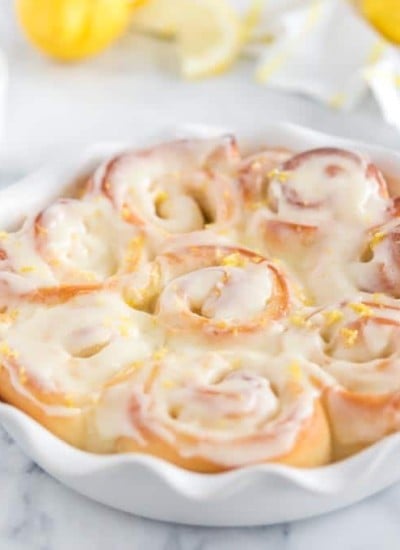 baked sweet rolls in white pie plate, with white dishes, lemons, and dish towel in background