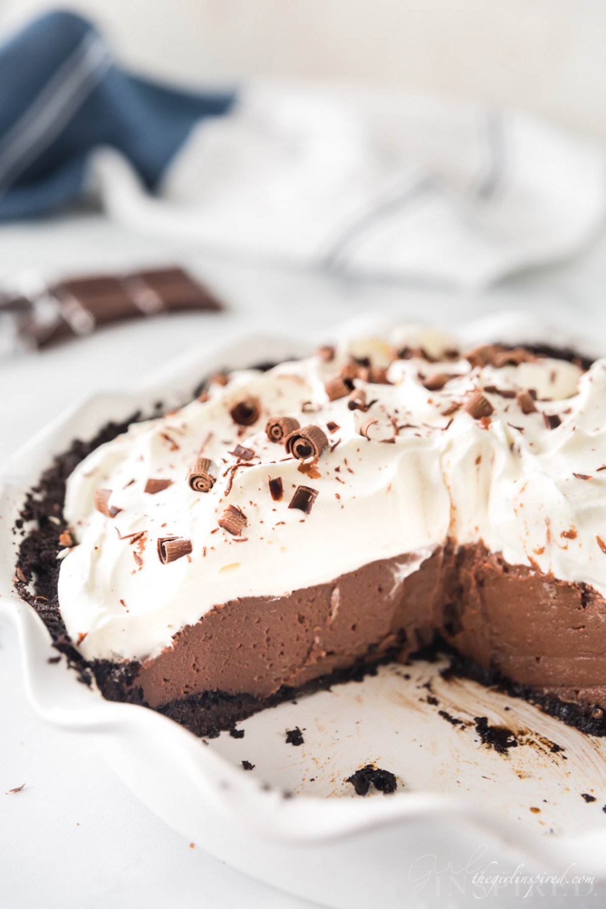 Chocolate cream pie, with several slices removed showing layers of cookie crust, chocolate custard filling, and whipped cream topping.