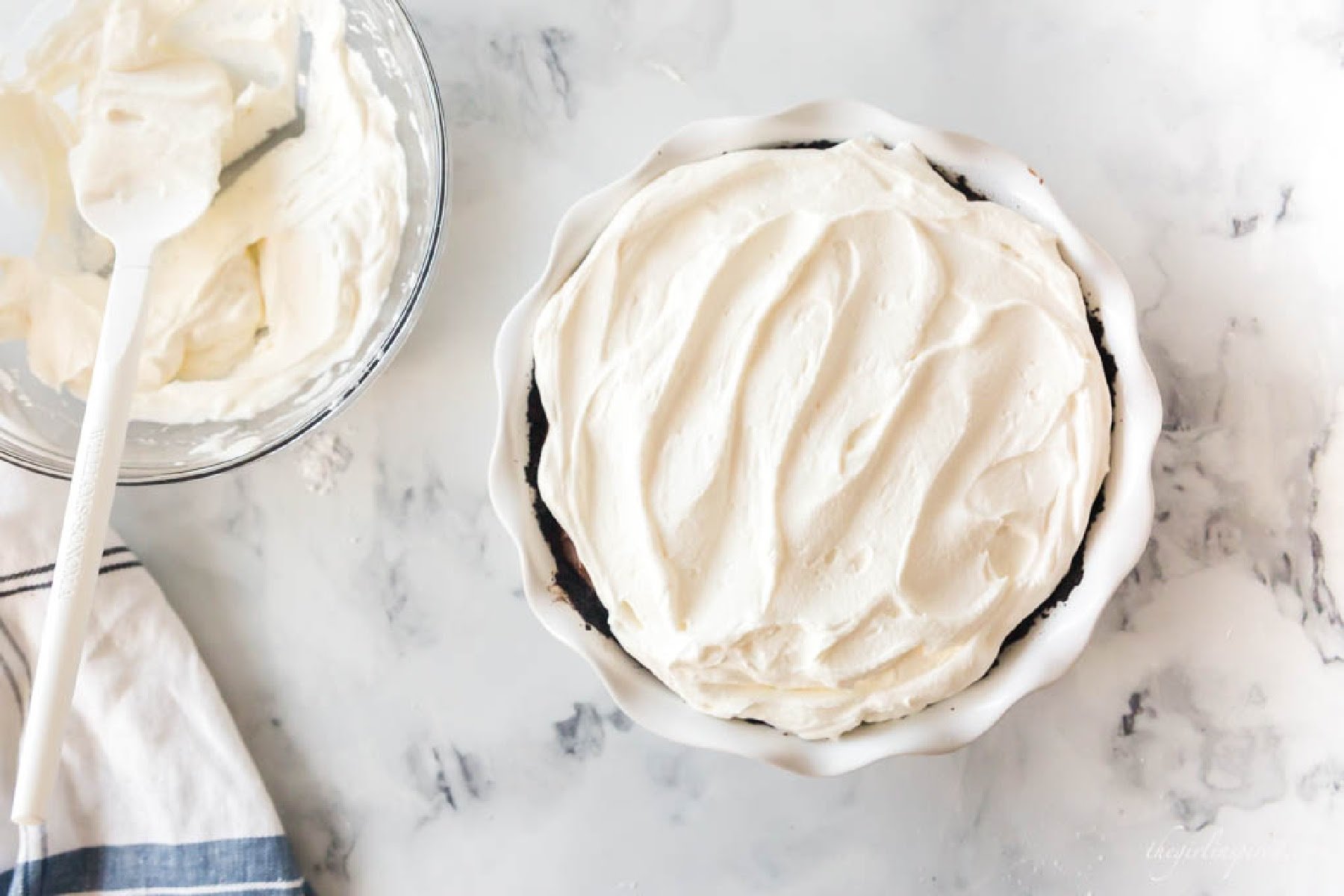 Topping the chocolate cream pie with whipped cream.