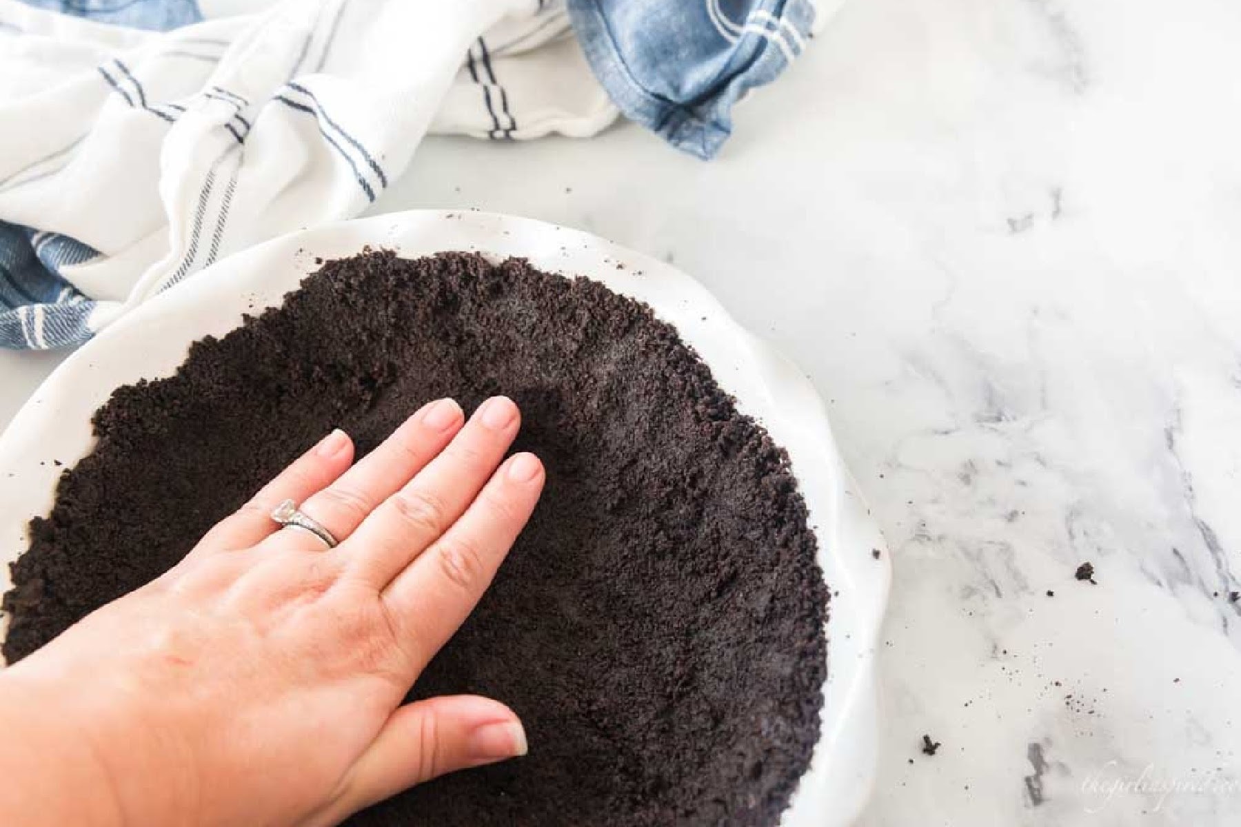 Pressing Oreo cookie crust into a pie plate with fingertips.