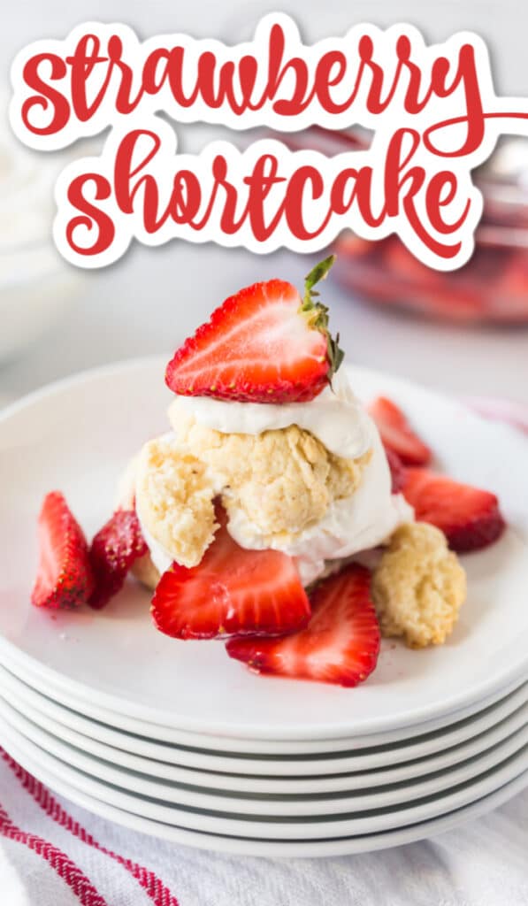 Strawberry shortcake biscuits, whipped cream, and fresh strawberries on a stack of white plates with text overlay