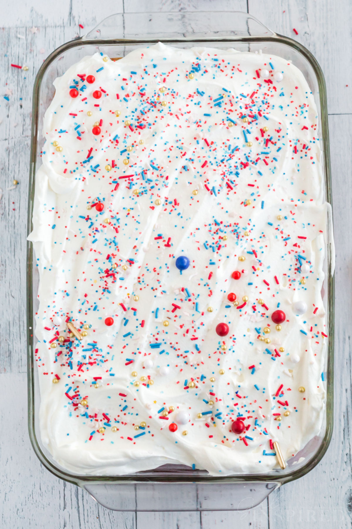 Cake topped with whipped cream and red, white, and blue sprinkles.