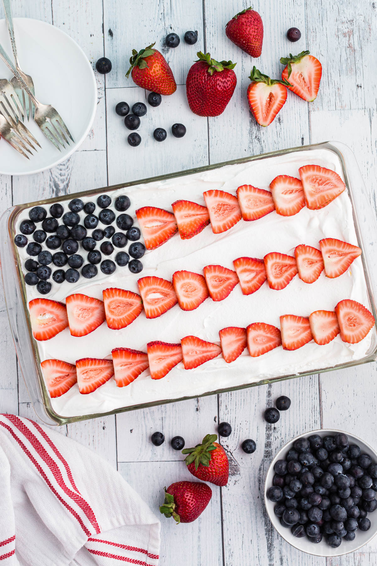 Blueberries and sliced strawberries forming a flag pattern over the top of the cake.