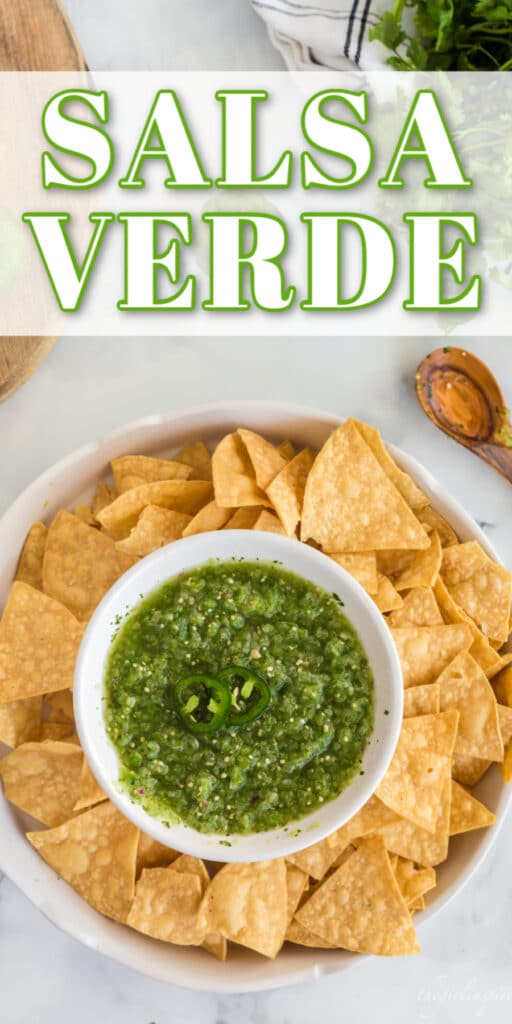 salsa verde in white chip'n'dip serving bowl with tortilla chips, wooden spoon, cilantro and jalapeño slices and wooden cutting board with text overlay