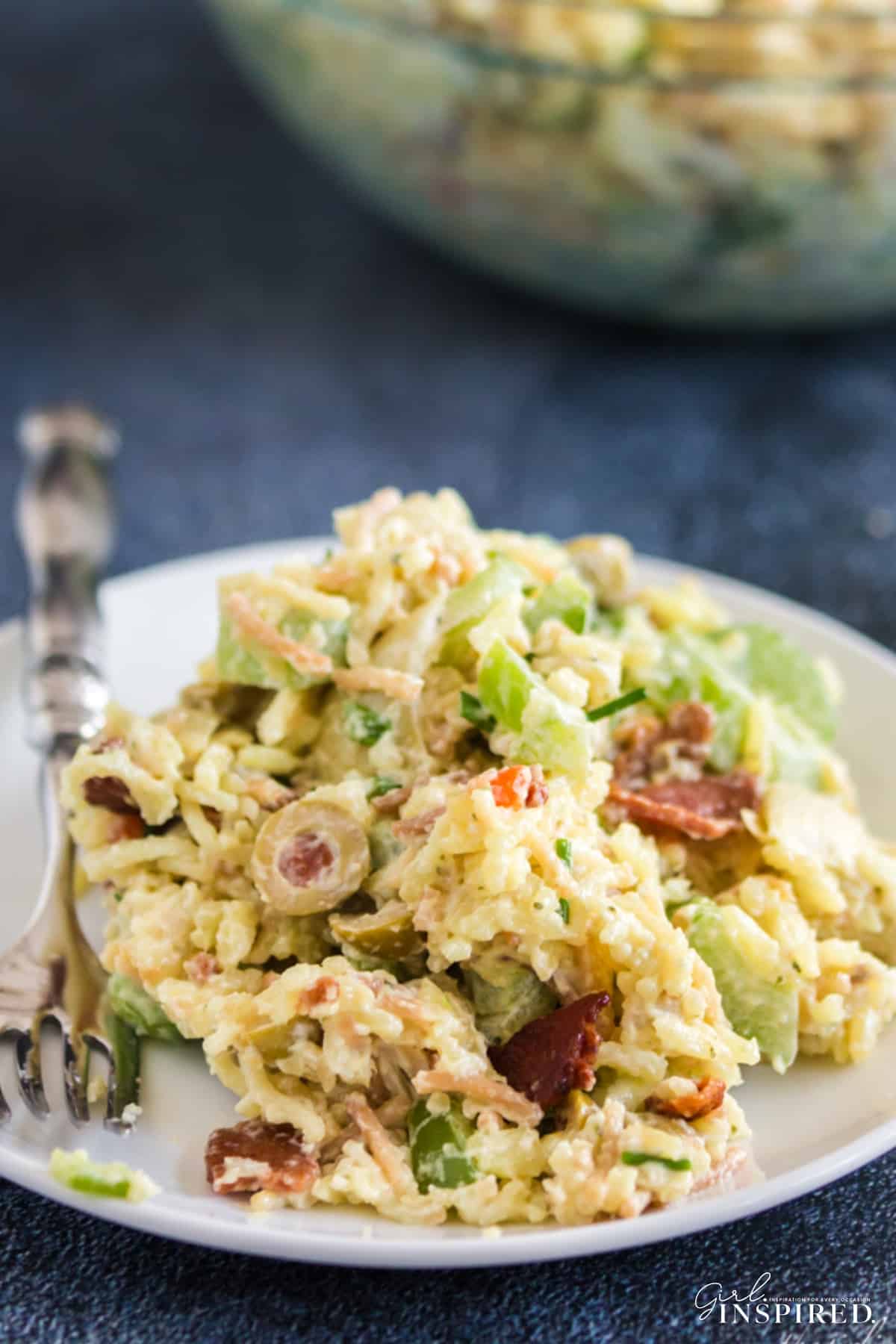 Serving of artichoke rice salad mounded on a white plate with fork.