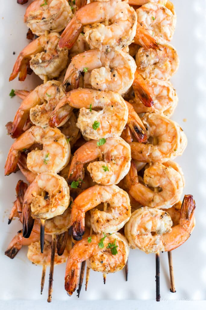 grilled shrimp skewers stacked on white plate