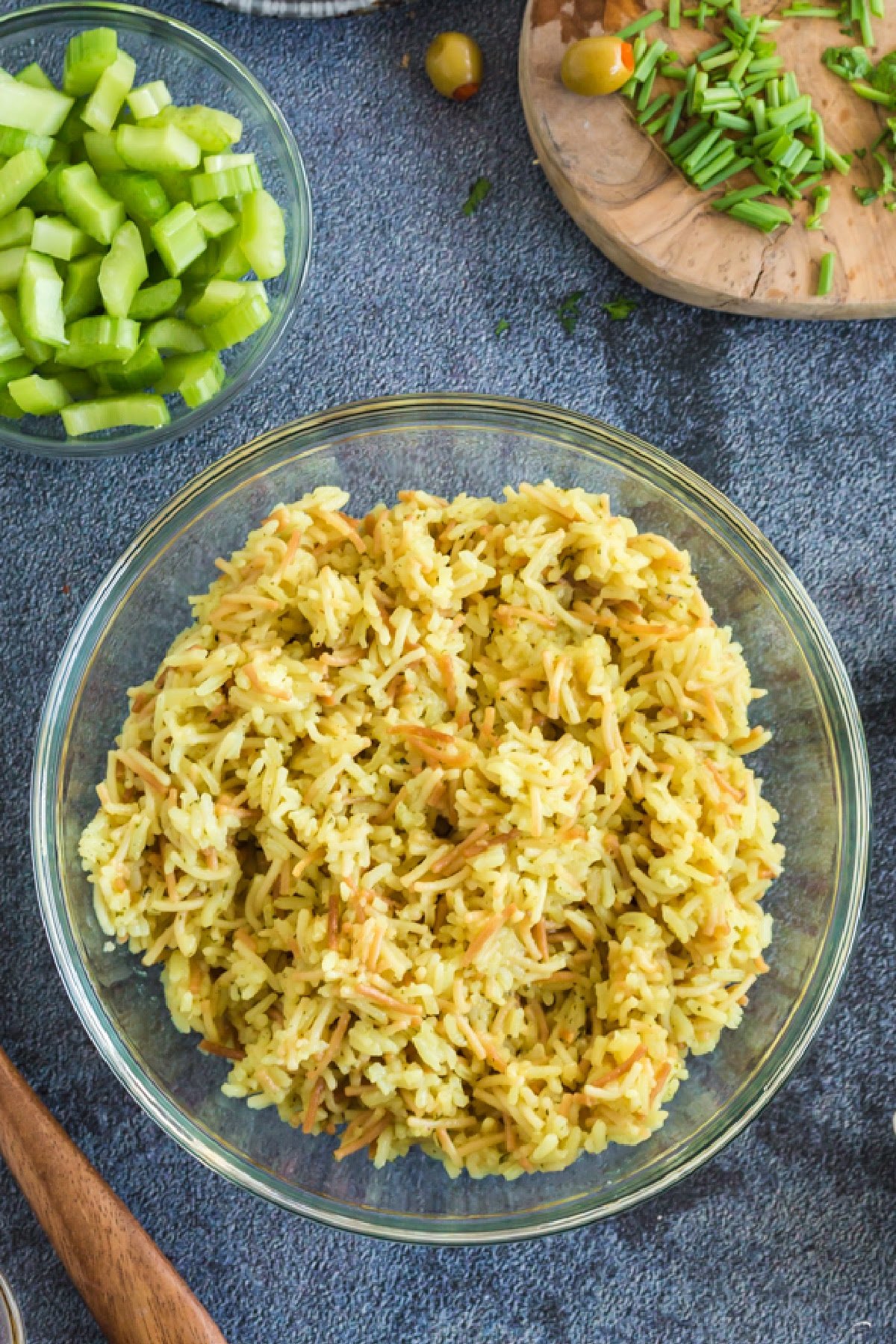 Glass bowl filled with cooked Rice a Roni, bowl of chopped celery and herbs.