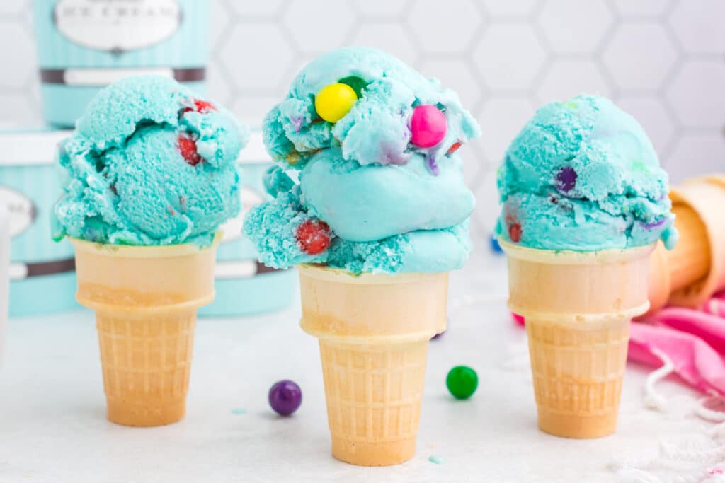 three ice cream cones with tall scoops of bubblegum ice cream