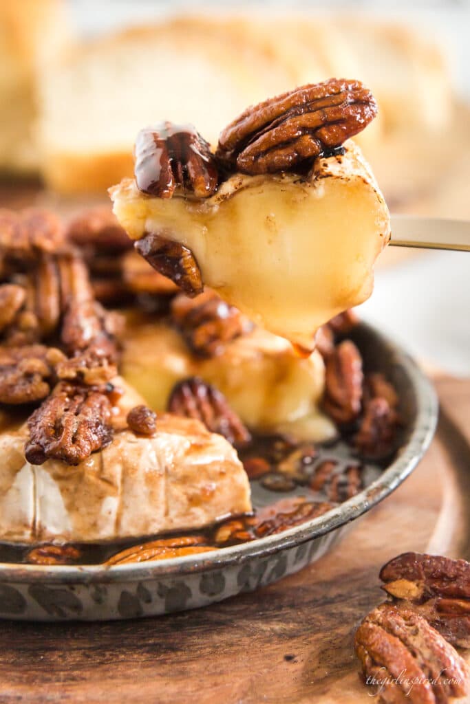 close up of melted brie slice with brandy soaked pecans baked on top