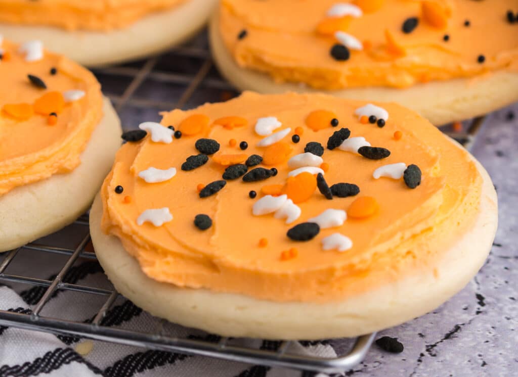 close up of lofthouse sugar cookie with orange frosting and Halloween sprinkles