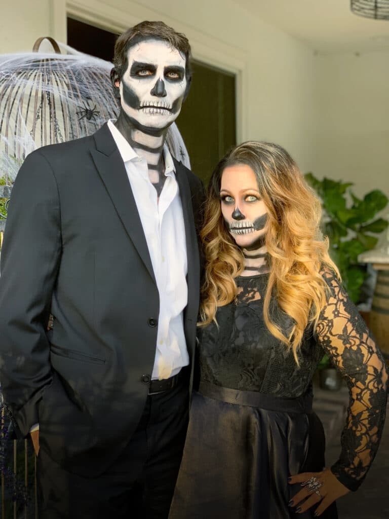 man and woman dressed in black suit and black lace dress with skeleton face makeup