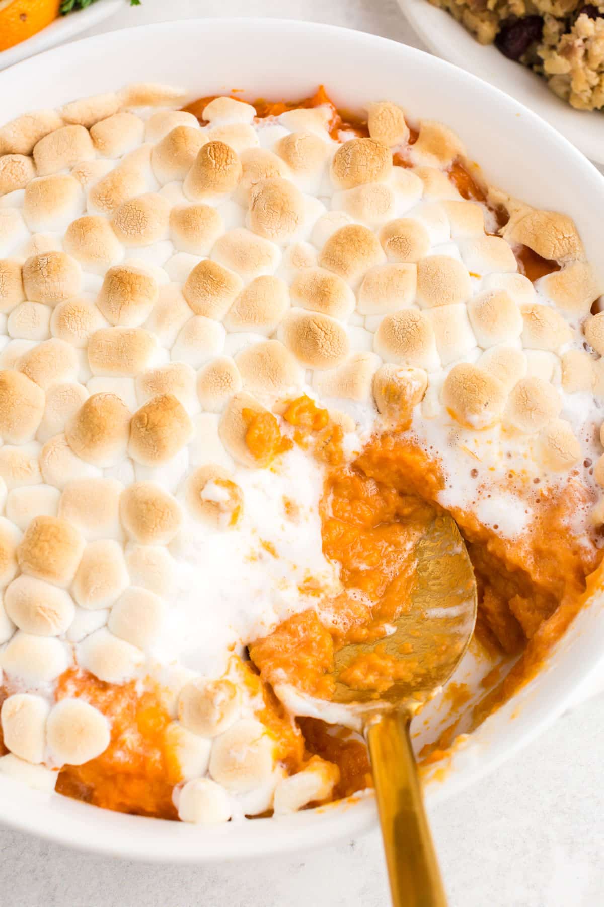 spoon scooping candied yams from casserole dish