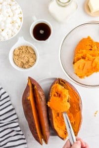 scooping orange flesh from sweet potato peels