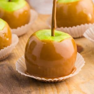 green apples coated in caramel in cupcake wrapper