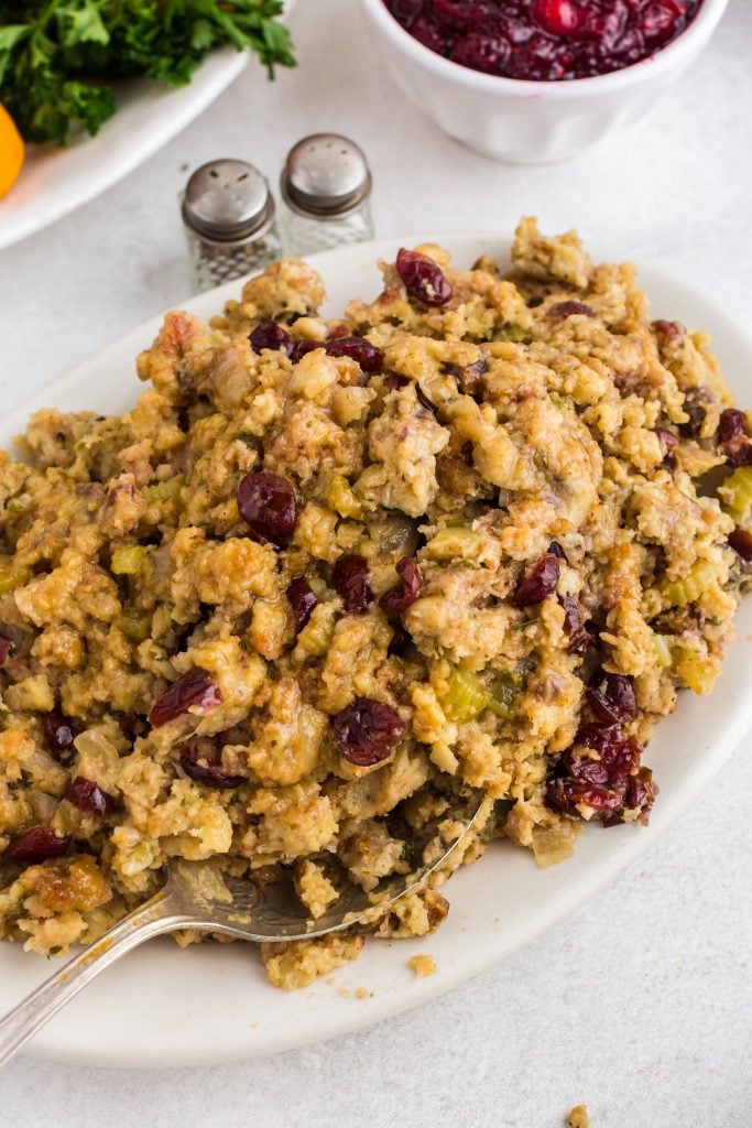 Thanksgiving Stovetop Stuffing on white serving platter with salt and pepper shakers and bowl of cranberry sauce in background