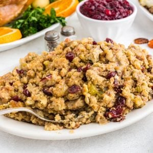 Thanksgiving Stovetop Stuffing on white serving platter with roasted turkey, salt and pepper shakers, and bowl of cranberry sauce in background