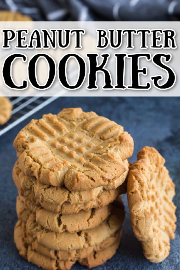 stack of peanut butter cookies with one cookie tilted against the side of stack; cooling rack with cookies in background