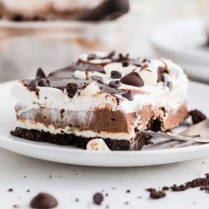 layered chocolate lasagna with pudding and whipped cream on white plate