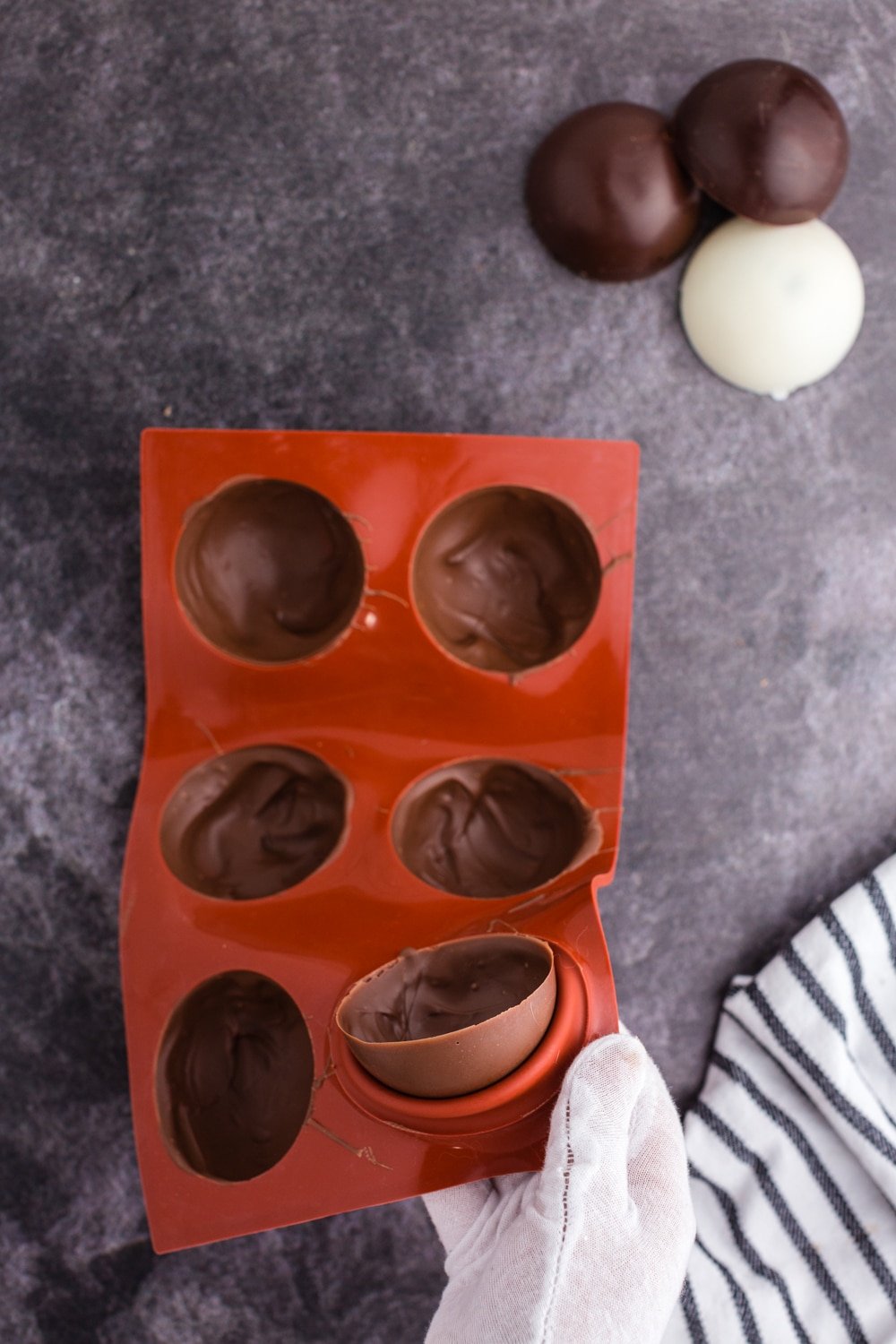 gloved hand pressing molded chocolate out of mold