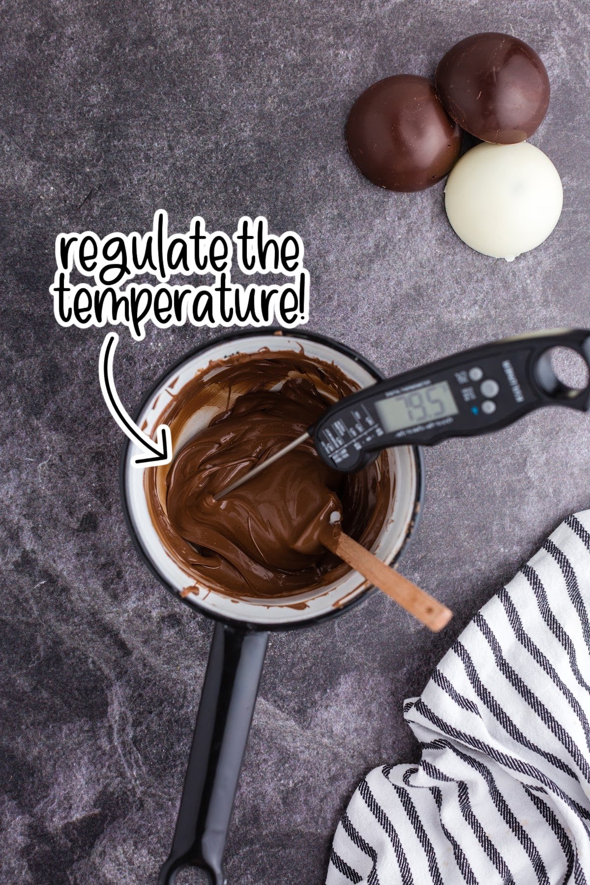 Spatula and digital thermometer in saucepan of melted chocolate; thermometer showing 79°F.