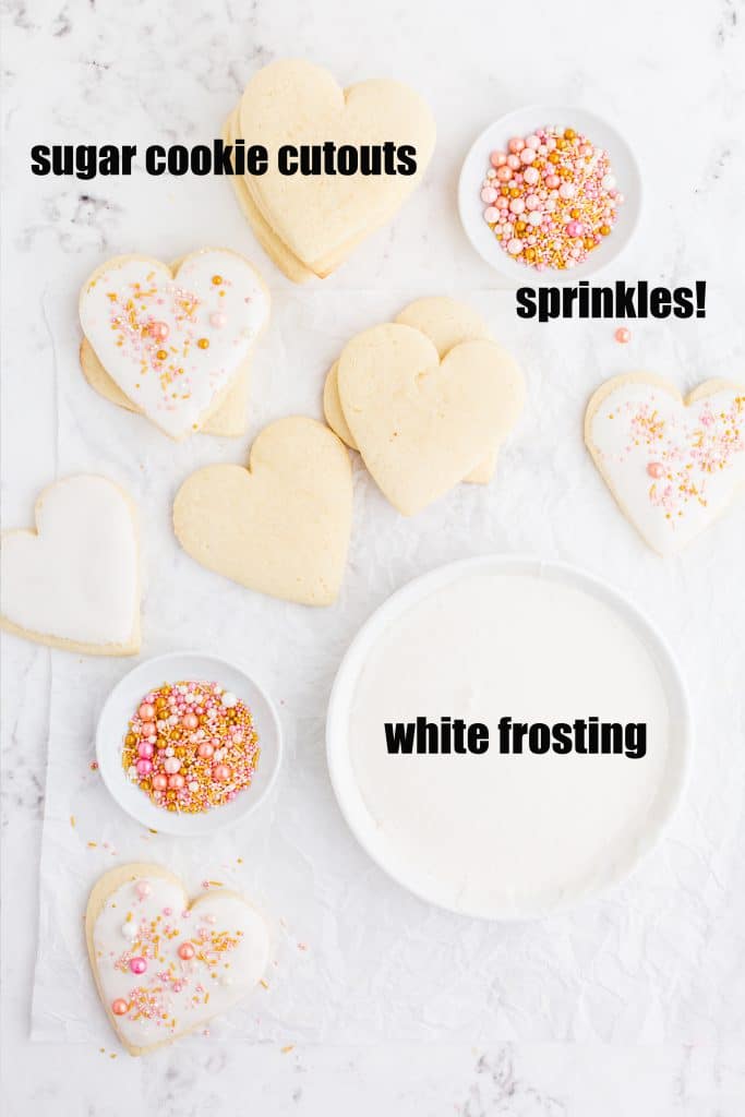 overhead photo of heart shaped Valentine's sugar cookies, some frosted, bowls of pink and gold sprinkles, plate with smooth white frosting, and text overlay