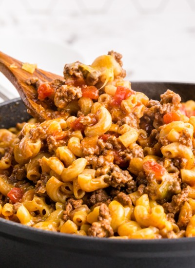 Chili Mac in saute pan with wooden spatula taking a scoop