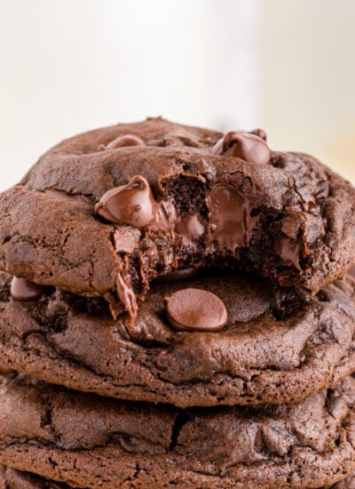 Stack of double chocolate chip cookies with gooey bite from top cookie.