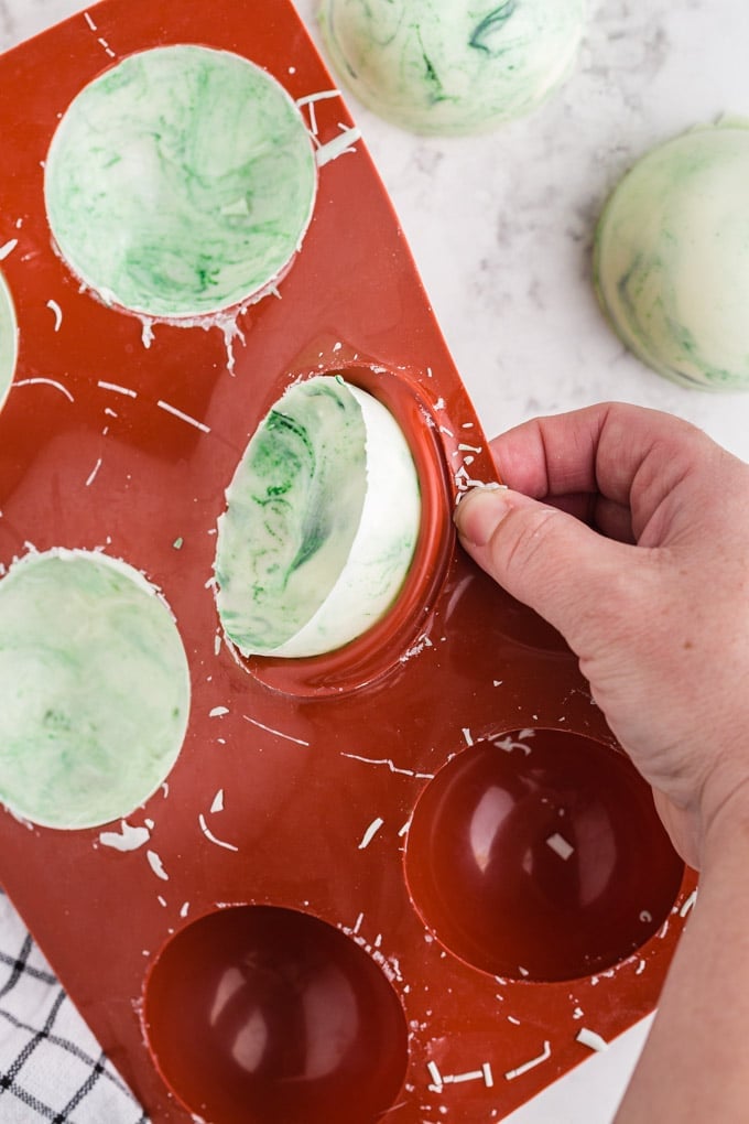 marbled green and white half sphere being popped out of silicone mold