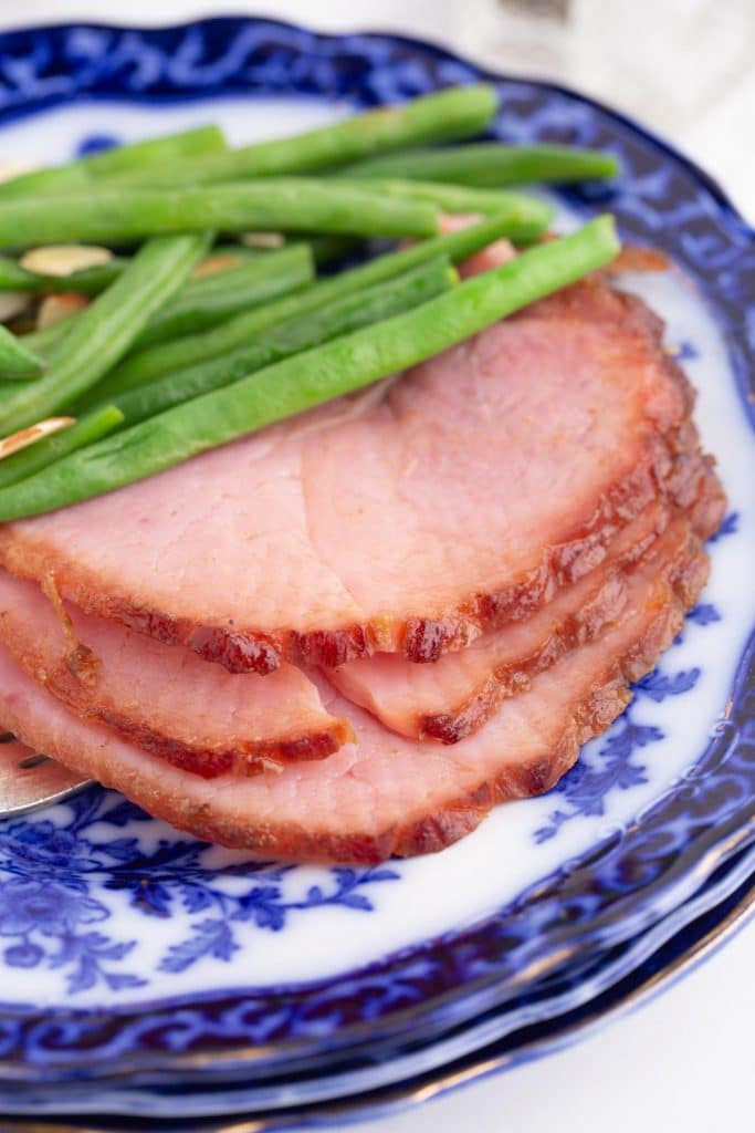 slices of ham and green beans on blue and white plates