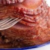 close up of sliced ham on blue platter with fork separating slices