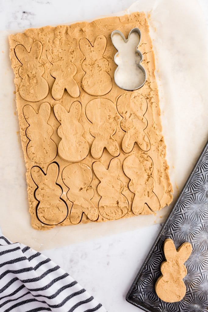 bunny cookie cutter pressed into peanut butter mixture with many shapes cut