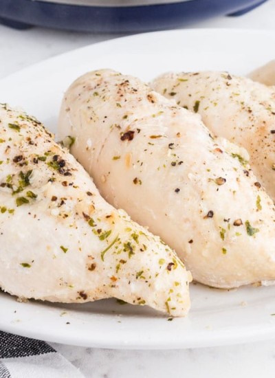cooked chicken breasts on white platter with instant pot in background