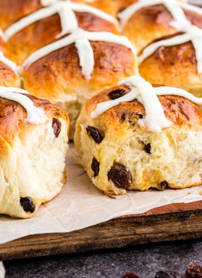hot cross buns on parchment paper and wooden cutting board