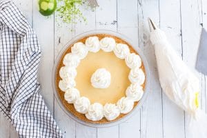 piping bag next to key lime pie with whipped cream piped on top