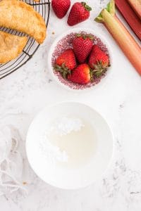 Bowl of powdered sugar, bowl with strawberries on marble countertop