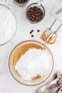powdered sugar mounded on top of peanut butter mixture in glass bowl