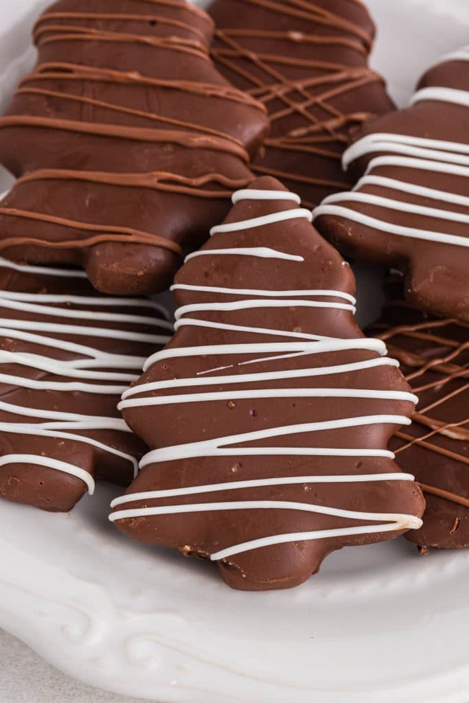 chocolate covered christmas tree cutouts with white and milk chocolate drizzle on white plate