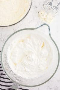 Glass mixing bowl with whipped heavy cream on a marble countertop