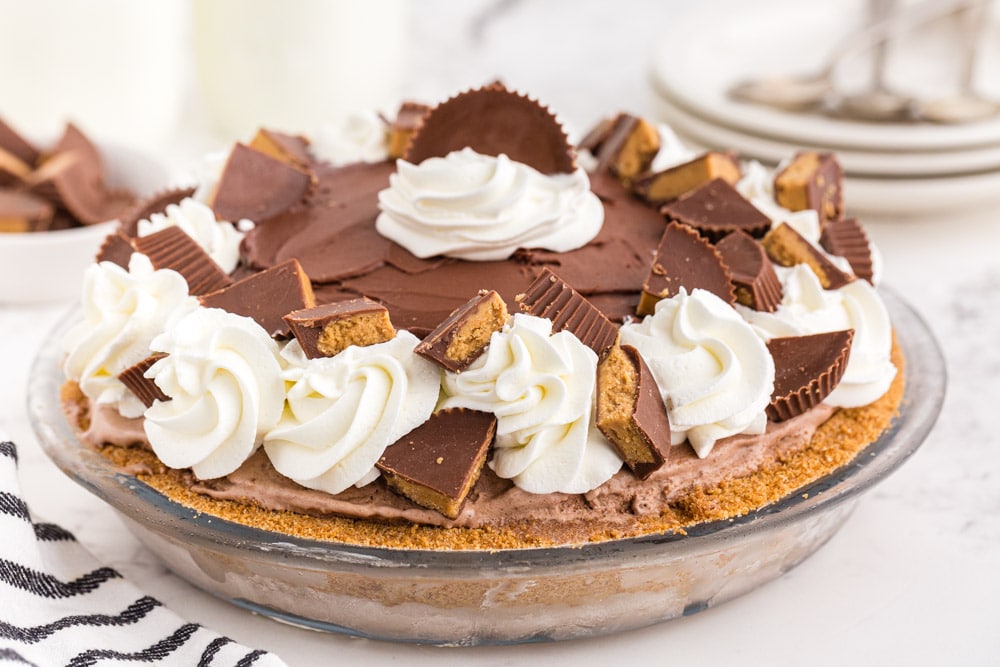 Glass pie dish filled with Peanut Butter Chocolate Ice Cream Pie on marble counter top