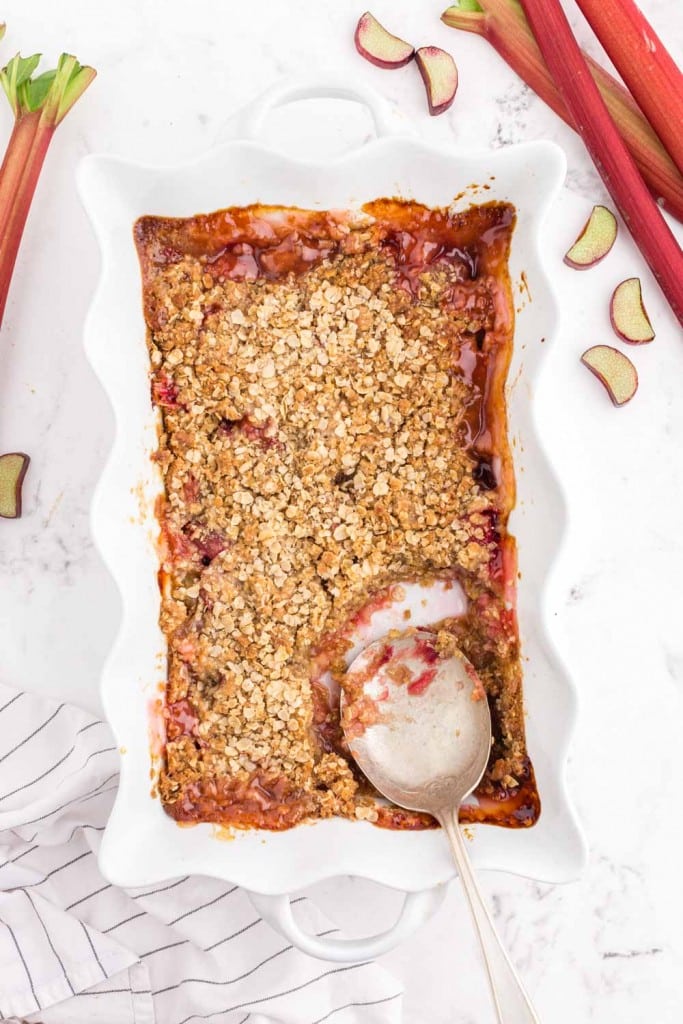 baked Rhubarb Crisp in white pie dish, silver serving spoon