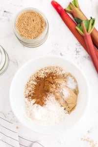 white mixing bowl with oats sugar cinnamon mixture on a marble countertop