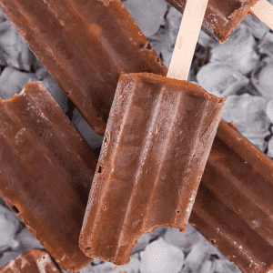 Four Fudgesicles on a batch of ice cubes, one bitten off