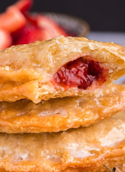 Stack of Strawberry Rhubarb Hand Pies with a bite in top pie.