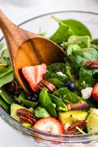 Close up of Strawberry Spinach Salad wit wooden serving spoon