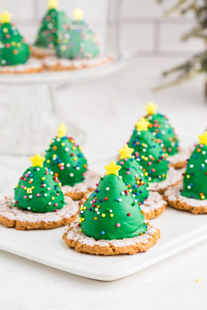 Chocolate covered strawberry christmas trees on a cake platter on a marble countertop