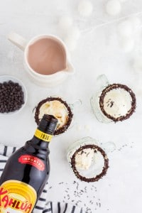 Kahlua poured into chocolate sprinkle rimmed glasses, hot chocolate on marble countertop