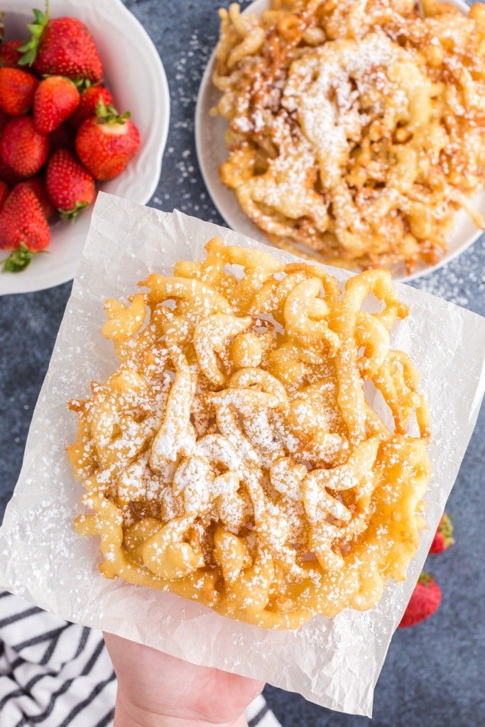 funnel cake on paper towel sprinkled with powdered sugar