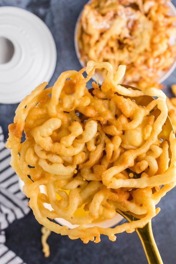 golden brown funnel cake lifted from the oil with slotted spoon