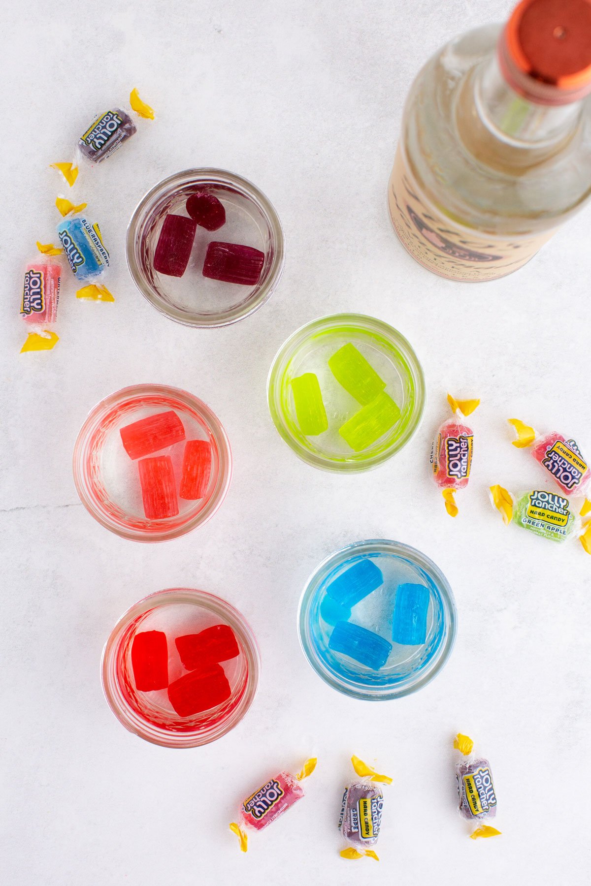 Mason jars with several Jolly Rancher candy pieces of the same color in each jar.